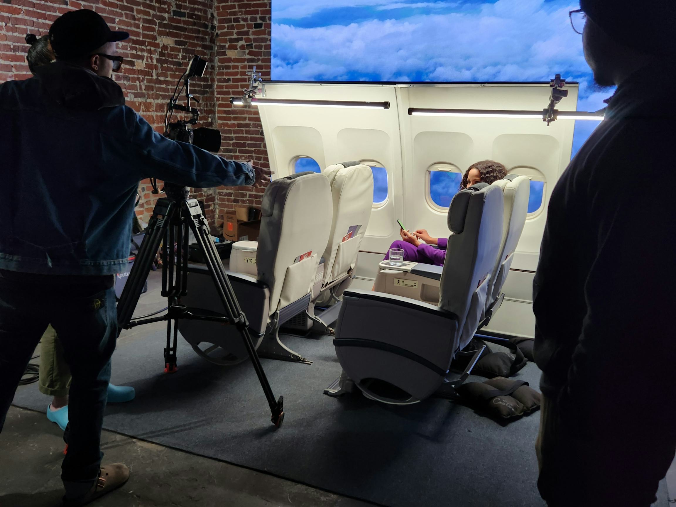 Crew filming on airplane cabin set with LED backdrop